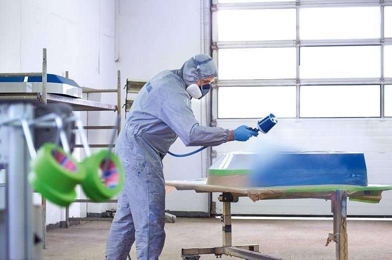 一名工人在表面喷漆，而tesa 4338高性能遮蔽胶带保护表面的其余部分。